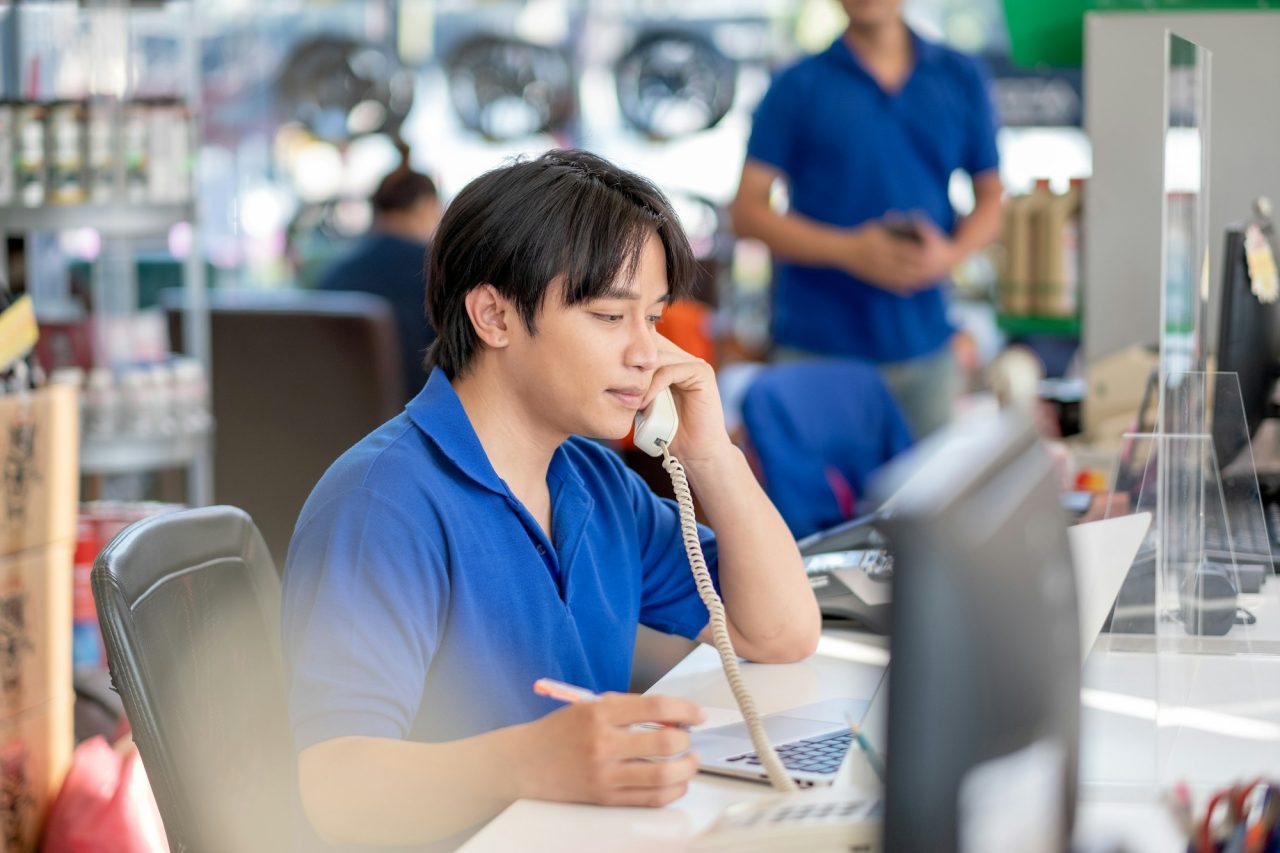 Asian man receive phone call from customer and stay in counter service