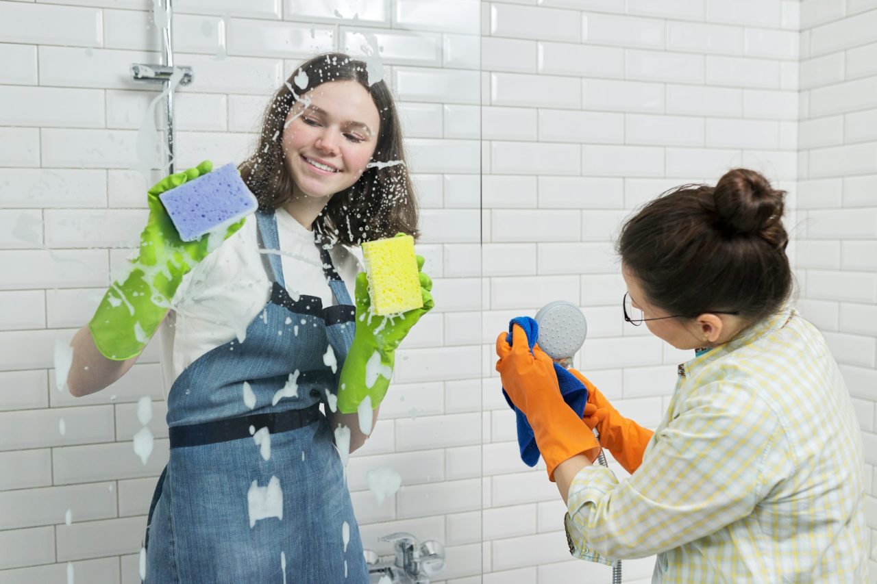 Mother and teenager daughter cleaning together in bathroom